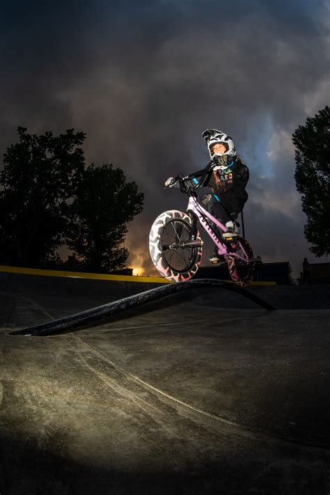 Photographe Maddy Mario en action, ajustant son appareil photo pour capturer un rider BMX.