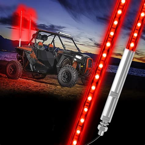 Une antenne fouet longue et lumineuse montée sur un quad dans un environnement tout-terrain, avec des lumières LED colorées allumées.