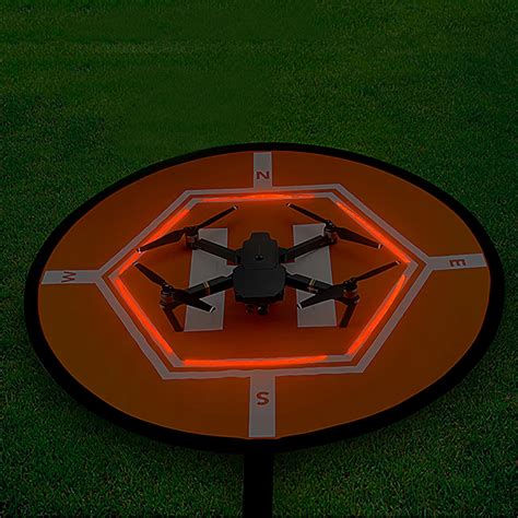 Photo d'un drone atterrissant sur un tapis d'atterrissage fixé au sol avec des piquets.
