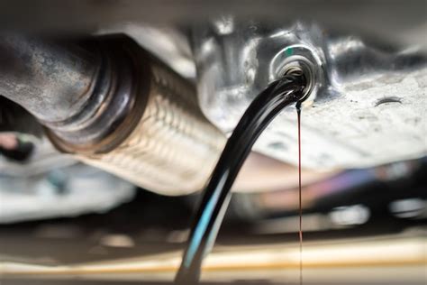 Photo illustrant le desserrage du bouchon de vidange moteur et l'écoulement de l'huile usagée.