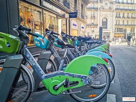 Vue générale du système Vélib' à Paris avec des vélos mécaniques et électriques dans des stations modernes.