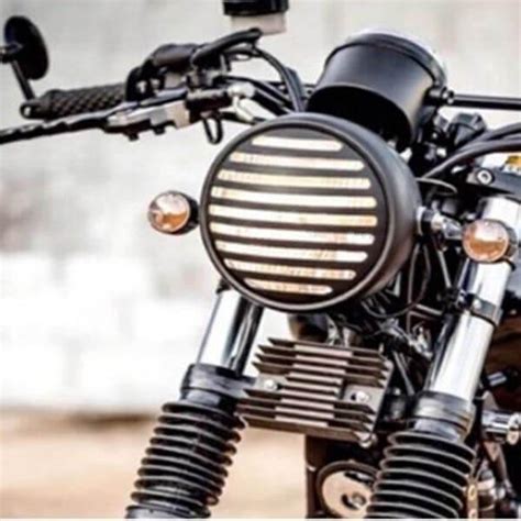 Moto customisée de type café racer avec un phare vintage rond et une grille de protection
