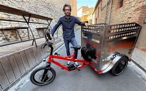 Photo d'un tricycle Camigo transportant des poubelles dans une rue étroite.
