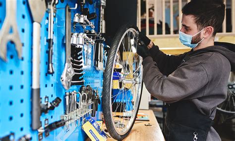 Illustration d'un atelier de réparation de vélos Intersport avec des techniciens travaillant sur différents types de vélos.