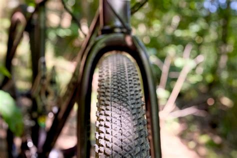 Gros plan sur un pneu de vélo gravel avec crampons sur un chemin de terre