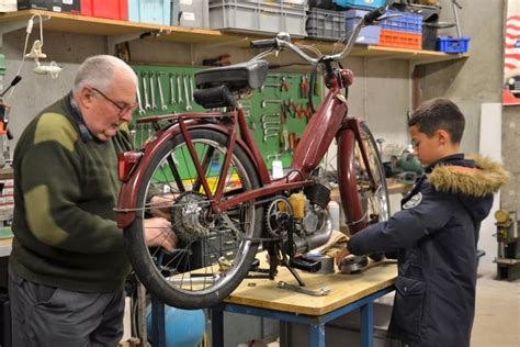Groupe de passionnés travaillant sur des mobylettes anciennes dans un atelier