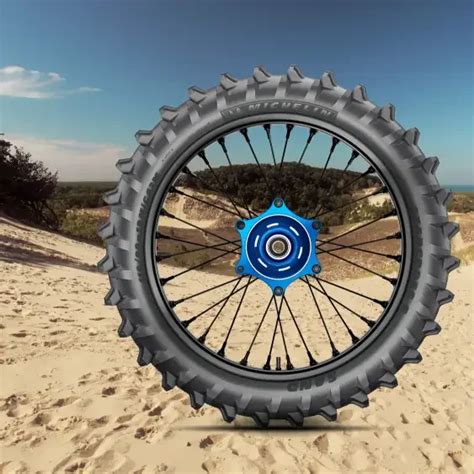 Gros plan sur un pneu de motocross spécifique pour le sable, avec des crampons espacés et profonds.