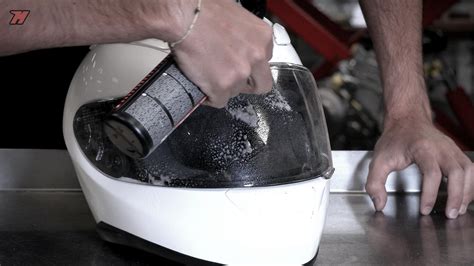 Image montrant un motard nettoyant sa visière avec une microfibre.