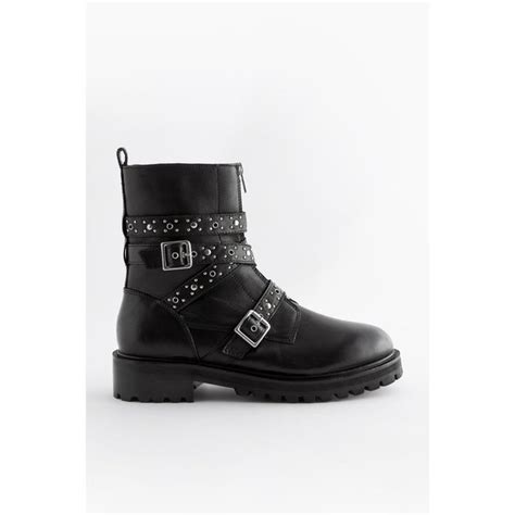 Gros plan sur les détails d'une botte style motard : boucles métalliques, coutures, semelle crantée.