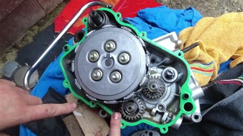 Vue du carter droit de la moto après retrait des premières protections, montrant l'accès à la roue dentée