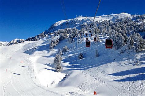 Vue panoramique de la station de Chamrousse avec des motoneiges sur une piste enneigée