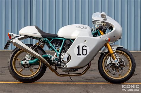Photo d'une Ducati Paul Smart 1000 rouge et blanche garée sur une route.