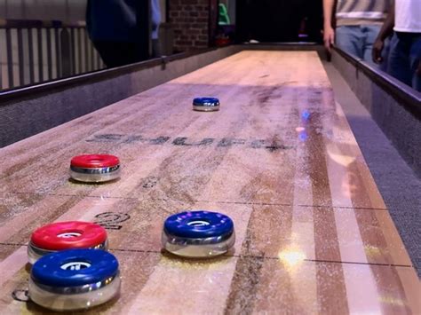 Photo des tables de shuffleboard et des cibles de fléchettes numériques dans l'espace jeux