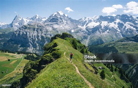 Photographie d'un coureur de trail sur un sentier de montagne avec vue panoramique