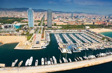Vue panoramique du Port Olympique de Barcelone, avec des voiliers et des bâtiments modernes.