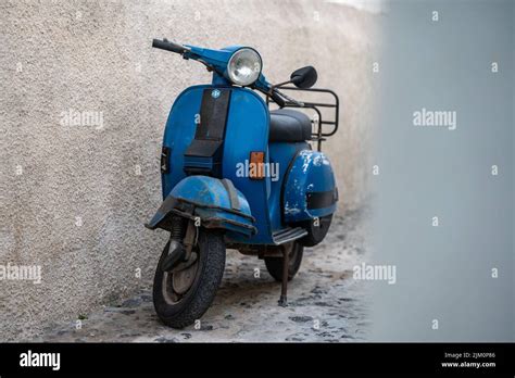 Vespa bleue vintage garée devant un mur bleu