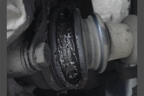Gros plan sur un soufflet de cardan déchiré avec projection de graisse